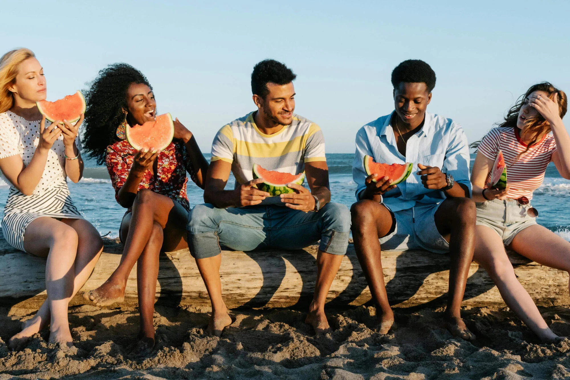 people at the beach eating watermelon